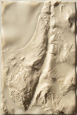  A purely tactile map — no ink at all — where terrain is pressed and embossed into thick vellum — valleys sunken, mountains raised — land visible only through shadow and touch. The map is dramatically lit to show the shadows.