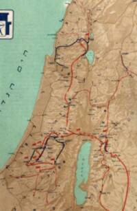 Hebrew labeling is used throughout. The map combines pale green-blue water, tan-to-brown hypsometric elevation tints, manual shaded relief, and overprinted red and black directional route lines.
