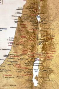 Full-color shaded-relief Bible atlas style with pale water, tan/brown bare-earth land, dark relief shadows, and mixed black/red place labeling.