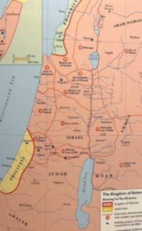 Modern atlas styling with pale blue water, peach/yellow regional fills, heavy red kingdom boundary, brown administrative division lines, and a thin gray graticule. Labels combine sans-serif city names with italic serif water and physical-feature labels and bold spaced serif regional names.